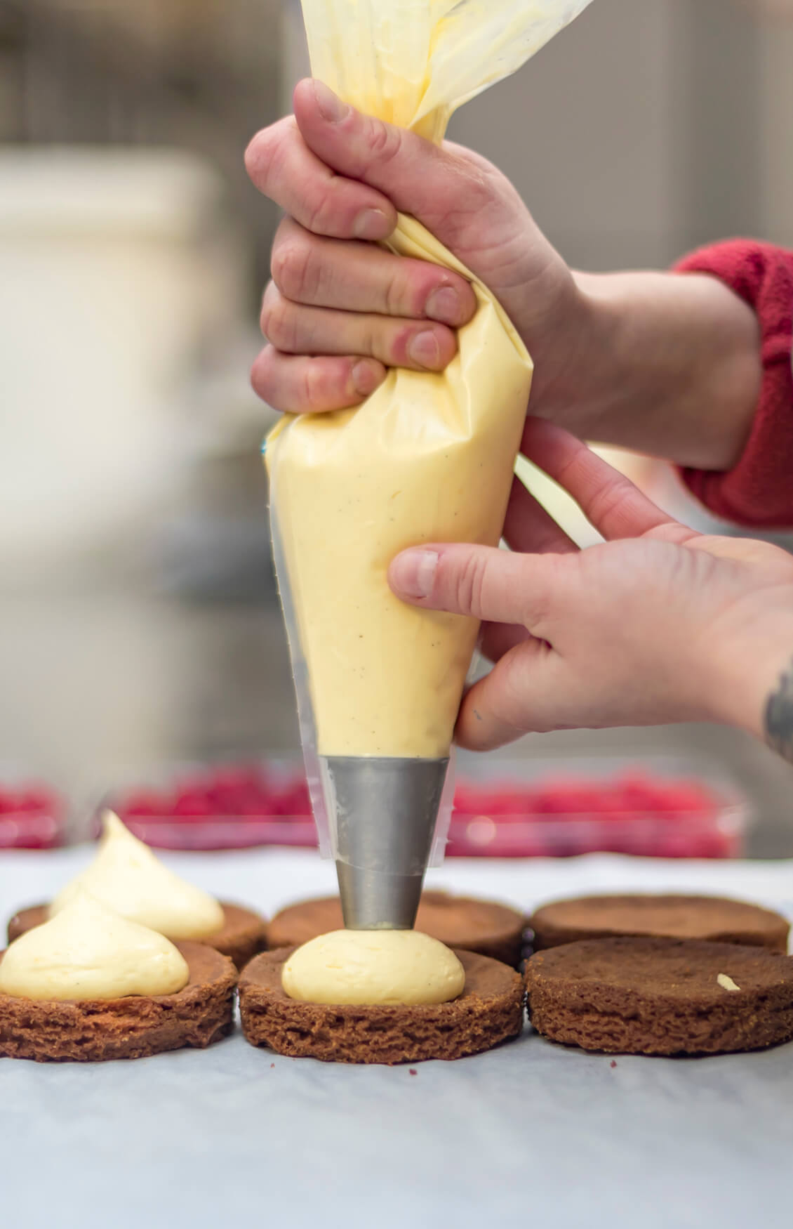 Garniture à la poche à douille de fonds de tartelettes à la crème, dans l’atelier du Fournil du Chablais